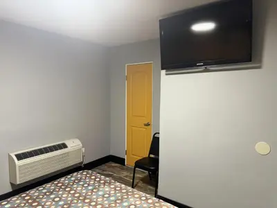 a room with a bed and a tv on the wall at Bob's Motel in Commerce