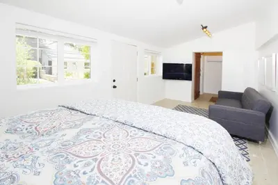 a white bedroom with a large bed and a couch at In The Village With Private Entrance in Claremont