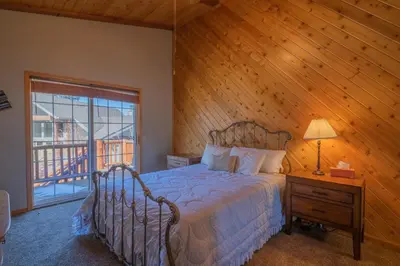 a bedroom with a bed and a wooden wall at Valley View Cabin in Big Bear Lake