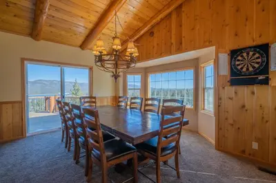 a dining room with a table and chairs and a clock at Valley View Cabin in Big Bear Lake