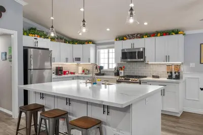 a kitchen with white cabinets and a large island with stools at Mickeys House by OC Adventure Homes in Anaheim