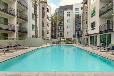 a large swimming pool with chairs and a building at Chic 1BR Retreat with Pool, Gym & Jacuzzi in Mid Wilshire & Miracle Mile in Los Angeles