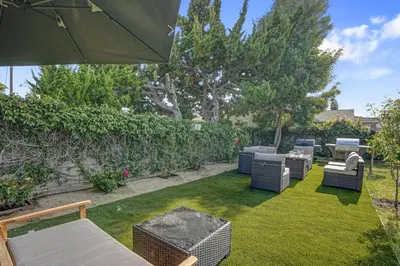 a backyard with chairs and tables and an umbrella at The Pacific Nest - 10min from LAX in Hawthorne