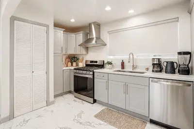 a kitchen with white cabinets and a sink and a stove at The Pacific Nest - 10min from LAX in Hawthorne