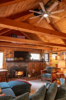 a living room with a ceiling fan and a fireplace at BunkHouse 1960's Camp Vibe with Timeless Wet Bar in Springville