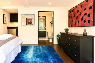 a bedroom with a bed and a blue rug at Enchanting Gated Hollywood Hills Oasis with Tranquil Treet-Top Views, Outdoor Living Room and Patios, Magical Zen Garden, Plus Bonus Romantic Guest House and Free Garage in LA's Most Desirable Central Serene Area, Sleeps 8-10 in Los Angeles