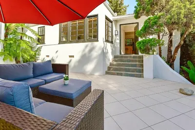 a patio with a couch and an umbrella at Enchanting Gated Hollywood Hills Oasis with Tranquil Treet-Top Views, Outdoor Living Room and Patios, Magical Zen Garden, Plus Bonus Romantic Guest House and Free Garage in LA's Most Desirable Central Serene Area, Sleeps 8-10 in Los Angeles