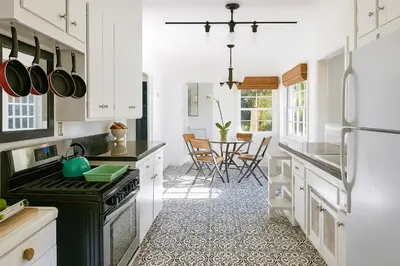 a kitchen with white cabinets and black appliances at Enchanting Gated Hollywood Hills Oasis with Tranquil Treet-Top Views, Outdoor Living Room and Patios, Magical Zen Garden, Plus Bonus Romantic Guest House and Free Garage in LA's Most Desirable Central Serene Area, Sleeps 8-10 in Los Angeles