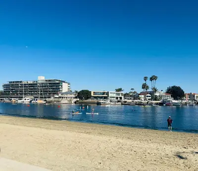 a person standing on a beach next to a body of water at Sea La Vie Beachhouse on the sand in Long Beach