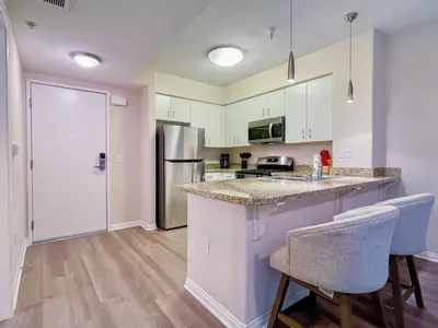 a kitchen with white cabinets and a counter with two chairs at Cozy Studio near Los Angeles Museum of Art in Los Angeles