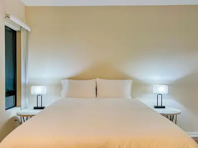 a bedroom with a large white bed with two lamps at Cozy Studio near Los Angeles Museum of Art in Los Angeles