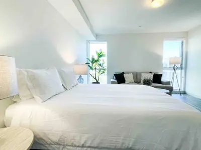 a bedroom with a large white bed and a couch at Studio Downtown Walk to Convention Center in Los Angeles