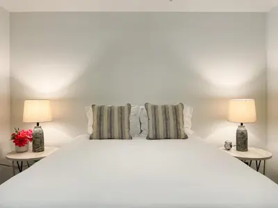 a bedroom with a large white bed with two lamps at Suite Downtown Pool and Gym Access in Los Angeles