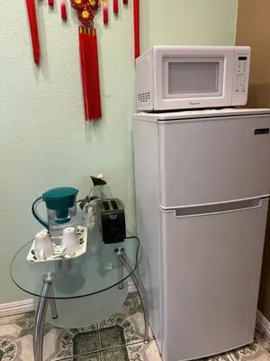 a microwave on top of a refrigerator with a glass table at Happy Room Near Citrus College in Glendora