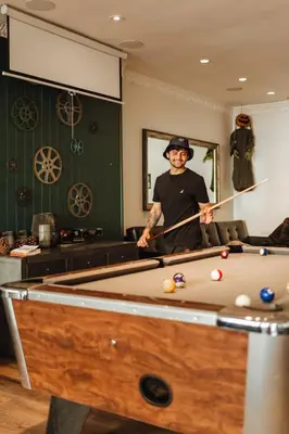 a man standing in a room with a pool table at Samesun Hollywood Hotel & Hostel in Los Angeles