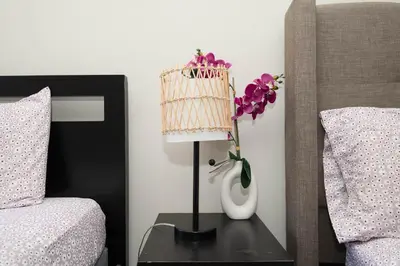 a vase of flowers on a table next to a bed at Hollywood Luxe 2BR Apartment with Rooftop Pool and Breathtaking Views in Los Angeles