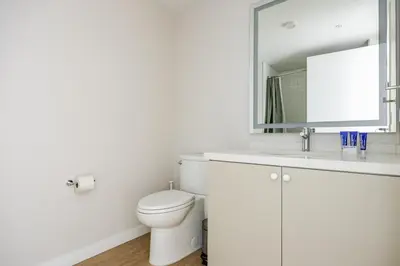 a white bathroom with a toilet and a mirror at Blueground Downtown elevator nr parks LAX-1247 in Los Angeles