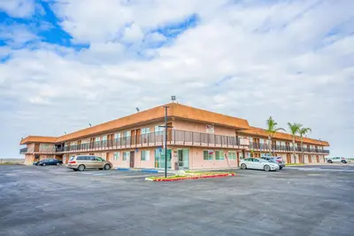 a large building with cars parked in a parking lot at Economy Inn Buttonwillow Bakersfield I-5 in Buttonwillow