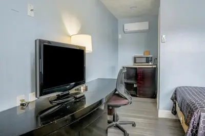 a hotel room with a desk with a tv and a bed at Economy Inn Buttonwillow Bakersfield I-5 in Buttonwillow