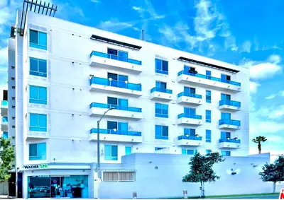 a white building with blue balconies on it at Cozy private room and bathroom in prime location with rooftop views 30 day stays or more in Los Angeles