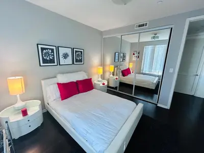 a bedroom with a bed with red pillows and a mirror at Cozy private room and bathroom in prime location with rooftop views 30 day stays or more in Los Angeles