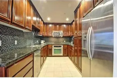 a kitchen with wooden cabinets and a stainless steel refrigerator at Cozy private room and bathroom in prime location with rooftop views 30 day stays or more in Los Angeles
