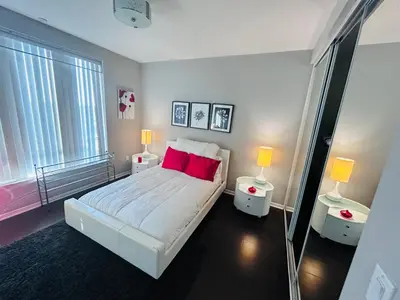 a bedroom with a bed with red pillows and two lamps at Cozy private room and bathroom in prime location with rooftop views 30 day stays or more in Los Angeles