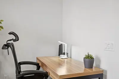 a wooden desk with a computer and a black chair at Gorgeous Family Home, Close to Frwys, Hospitals & Sports Arenas, Pets OK in Orange
