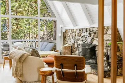 a living room with a stone fireplace and chairs at Luxury A-Frame Retreat in Lake Arrowhead