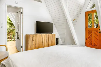 a bedroom with a bed and a tv on a wooden cabinet at Luxury A-Frame Retreat in Lake Arrowhead