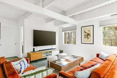 a living room with white walls and a flat screen tv at Luxury A-Frame Retreat in Lake Arrowhead
