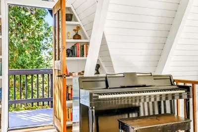 an open door to a porch with a piano at Luxury A-Frame Retreat in Lake Arrowhead