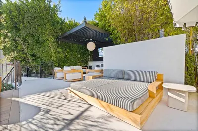 a wooden couch sitting on a patio with chairs at Casa Cortona by Stay Awhile Villas in Los Angeles