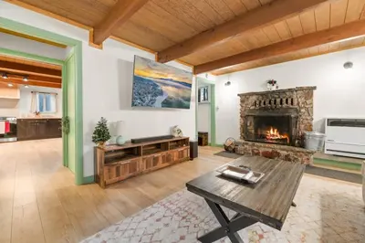 a living room with a fireplace and a table at Midnight Pines Cabin - Cozy Get-Away Near Slopes! in Big Bear Lake