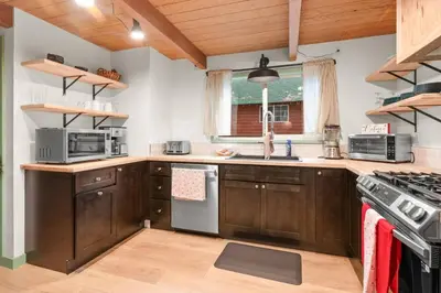 a kitchen with wooden cabinets and a stove top oven at Midnight Pines Cabin - Cozy Get-Away Near Slopes! in Big Bear Lake