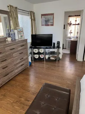 a living room with a television and a wooden floor at B and G Studio Space Guesthouse in San Bernardino