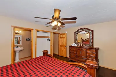 a bedroom with a bed with a ceiling fan and a mirror at Big 10 Luxury Cabin/Walk to Snow Summit- HotTub in Big Bear Lake