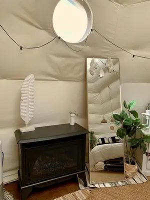 a living room with a fireplace and a mirror at Stunning Geo Dome with Joshua Tree vibes in Palmdale