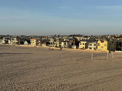 a view of a beach with houses in the background at Oceanfront 2 BR w Pool & Parking 234 in Hermosa Beach