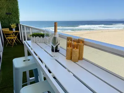 a table with a bottle of wine and glasses on the beach at Oceanfront 2 BR w Pool & Parking 234 in Hermosa Beach