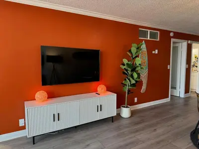 a living room with a tv on an orange wall at Oceanfront 2 BR w Pool & Parking 234 in Hermosa Beach