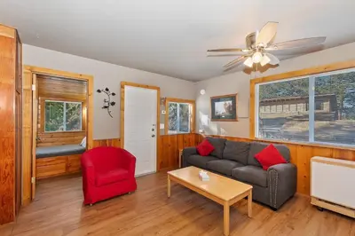 a living room with a couch and a red chair at Rosy Cozy Cottage-Walk to Big Bear Lake in Big Bear Lake