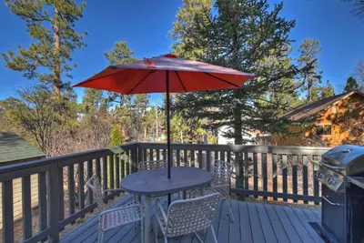 a table with an umbrella on a deck at Rosy Cozy Cottage-Walk to Big Bear Lake in Big Bear Lake