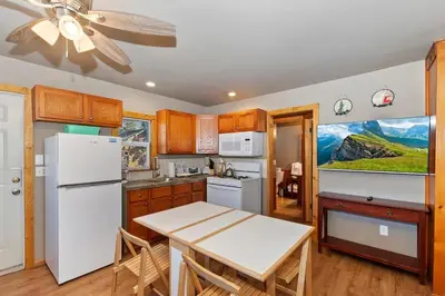 a kitchen with a white refrigerator and a table at Rosy Cozy Cottage-Walk to Big Bear Lake in Big Bear Lake