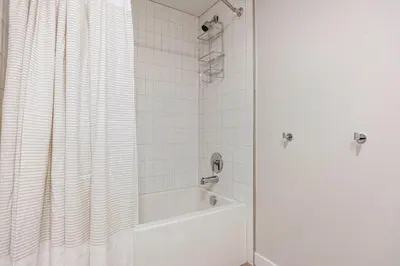 a bathroom with a tub and a shower curtain at Blueground Downtown elevator nr parks LAX-1248 in Los Angeles