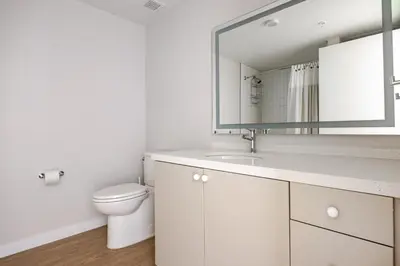 a white bathroom with a toilet and a mirror at Blueground Downtown elevator nr parks LAX-1248 in Los Angeles