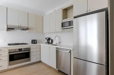 a kitchen with white cabinets and a stainless steel refrigerator at Blueground Downtown elevator nr parks LAX-1248 in Los Angeles