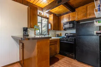 a kitchen with wooden cabinets and a black refrigerator at Cozy 2BR Retreat Near Lake Grego with Mountain Views in Crestline