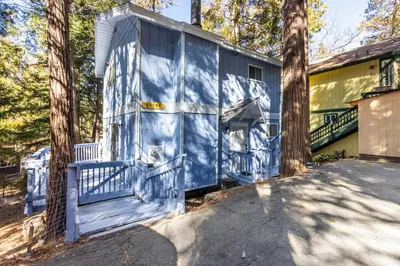 a blue house with a porch and trees at Cozy 2BR Retreat Near Lake Grego with Mountain Views in Crestline