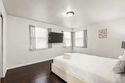 a white bedroom with a bed and two windows at Spacious Retreat w Large Kitchen & Outdoor Patio in Pasadena